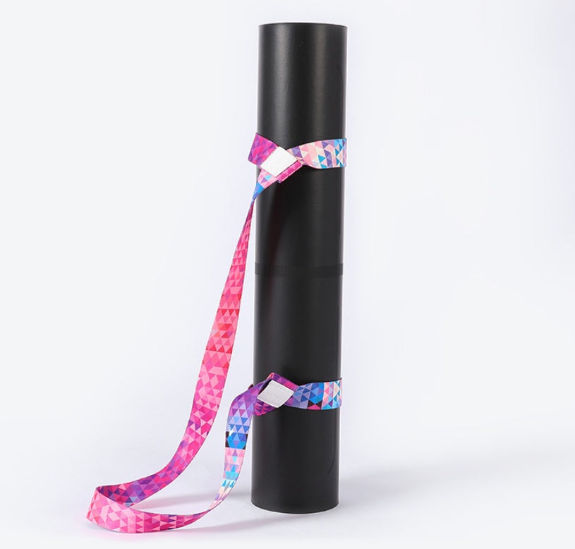 Yoga mat strap securely holding a rolled black yoga mat. Adjustable and durable cotton material with a colorful geometric design.