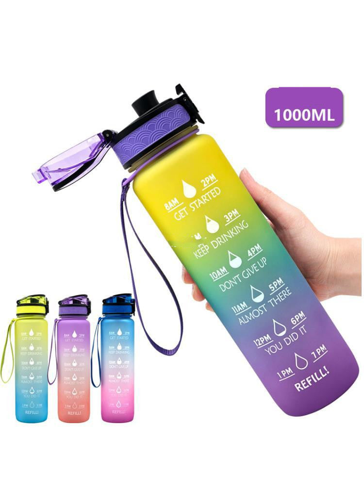 Rainbow gradient 1000ml water bottle with motivational time markers, flip-top lid, and wrist strap for easy carrying.